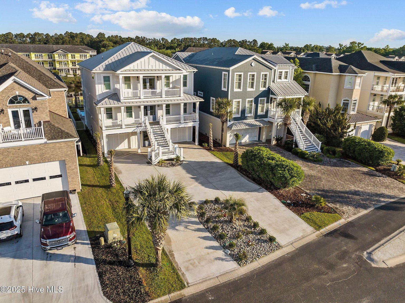 Aerial view of 4843 Williams Island Drive , the three-story white coastal residence centered among neighboring Paradise Island homes, palm trees and patio pavers visible from above