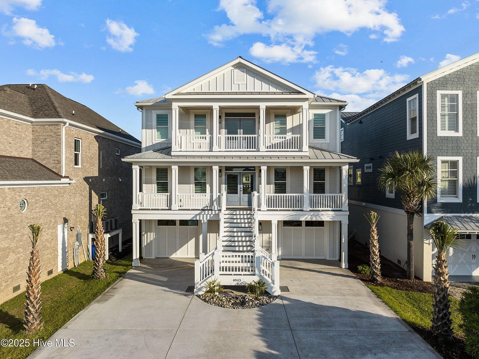 4843 Williams Island Drive , coastal three-story white waterfront residence in the gated Paradise Island community, warm afternoon light, palm trees framing the porches